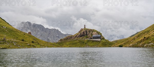 View over the Wolayersee lake to Alpenvereinshütte Wolayerseehütte, cloudy mountain landscape,
