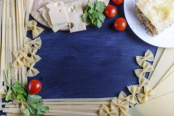 Frame with italian pasta ingredients on black wooden background. copy space, top view