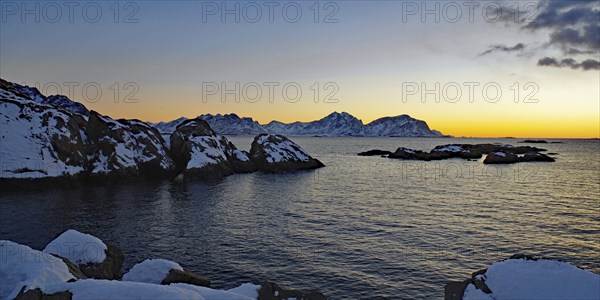 Impressive winter landscape with snow-covered mountains and rocks in a calm sea at sunset, Winter,