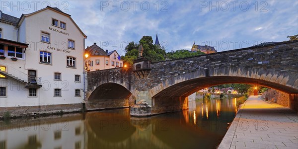 Town view of Vianden with the old stone bridge over the river Our and the castle in the evening,