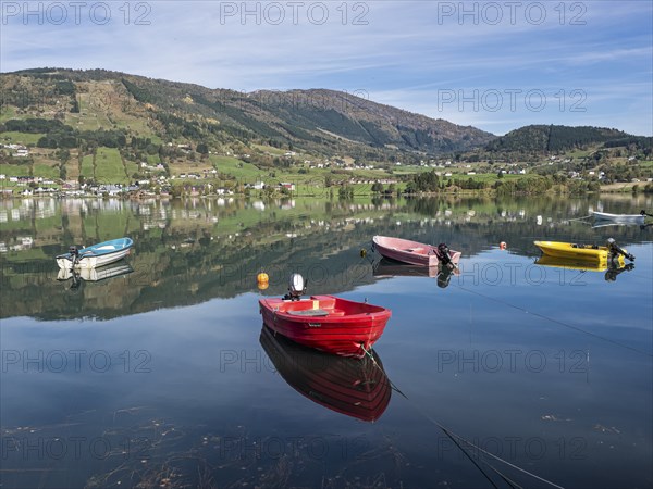 Boats on the calm lake Hafslovatnet, mountains reflected in the lake, Sognefjord region, Norway,