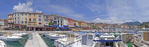 A picturesque harbour with numerous boats, colourful buildings and restaurants under a blue sky