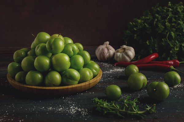 Tkemali, green cherry plum, with ingredients for sauce, cilantro, mint, hot pepper, garlic, on a