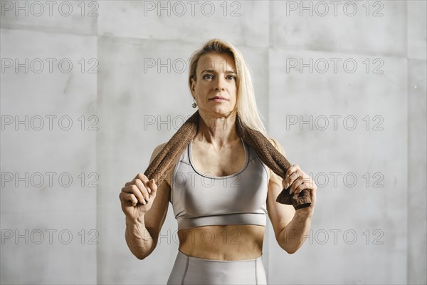 Middle-aged woman bodybuilder holding a towel thrown over her neck