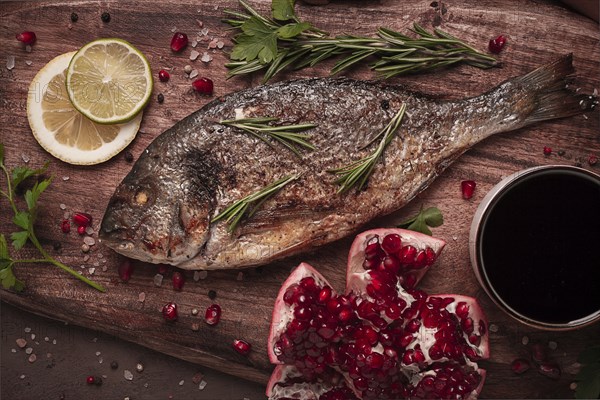 Fried dorado fish, with spices and herbs, on a wooden board, pomegranate sauce, close-up, no people