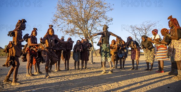 Group of traditional Himba woman with Cief of the village standing in a semicircle, clapping and