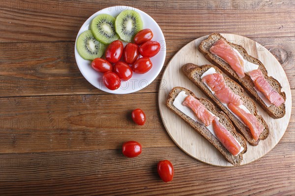 Smoked salmon sandwiches with butter on wooden background. cherry tomatoes. top view, copy space