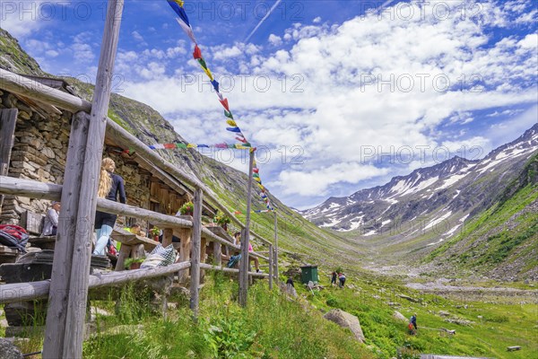 Scenery with a mountain farm, colourful flags and a path through the green mountain landscape under
