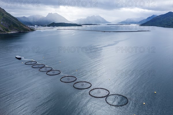 Aerial view of a salmon farm, rainy weather, grey sky, village Myre in the back, Vesteralen