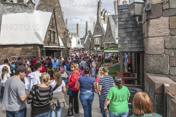 Theme park guests walk through Hogsmeade in The Wizarding World of Harry Potter at Universal