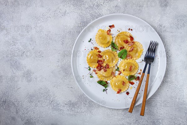 Fresh ravioli, with butter, spices and herbs, fried bacon, on the table, top view, light