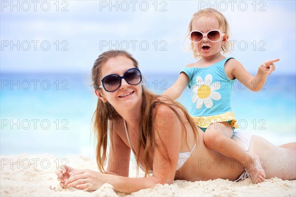 A young woman with baby relaxing on the beach, La Digue, Indian Ocean, Seychelles, Africa
