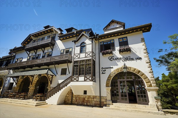 Historic white hotel with half-timbered walls, balconies and parasols on a sunny day, Elafos Hotel,