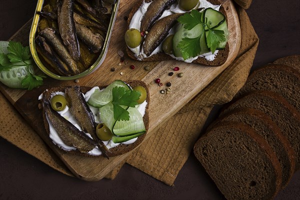 Sandwiches, black bread with sprats, cream cheese, cucumbers, on a cutting board, top view,