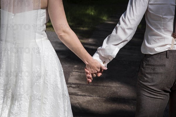 A bride and groom walk hand in hand to their church wedding on 14 June 2016