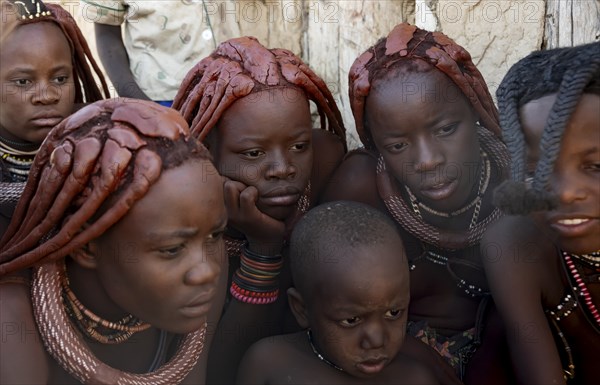 Group of Himba children and young woman look at pictures on a camera, near Opuwo, Kaokoveld,