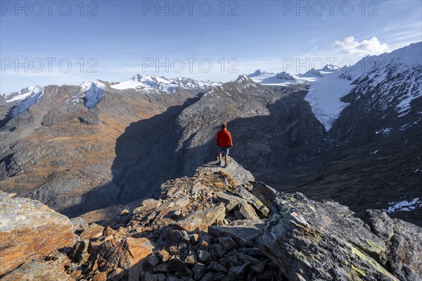 Mountaineer standing on a rock, surrounded by an impressive mountain landscape with snow-covered