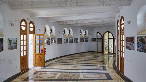Light-flooded hallway with marble floor and wooden doors, decorated with square windows and