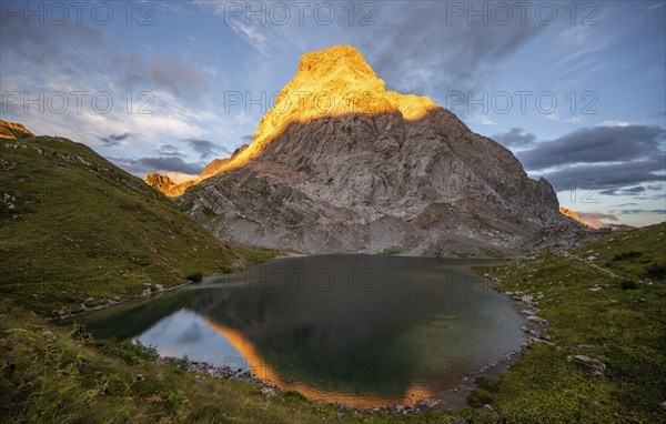 Alpenglow at Seekopf or Monte Capolago, reflection in Wolayersee, mountain landscape with green