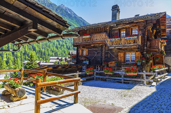 Old wooden house with floral decorations on windows and terrace, historic village centre, Grimentz,