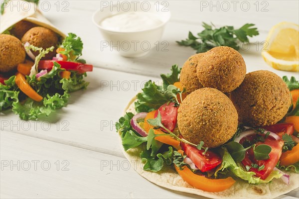 Tortillas, wrapped falafel balls, with fresh vegetables, vegetarian healthy food, on a wooden white