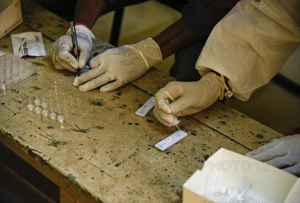 Health worker in personal protective equipment (PPE) collects a nasal swab sample from locals for