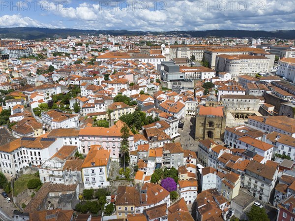 Dense urban environment with old red tiled roofs and historic architecture under a cloudy sky,