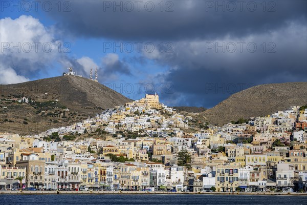 View of the town of Ermoupoli with pastel-coloured houses and sea, on the hill Basilica of San