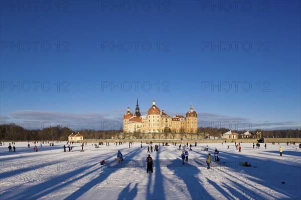 Moritzburg, castle park in winter with ice skaters on the frozen castle pond