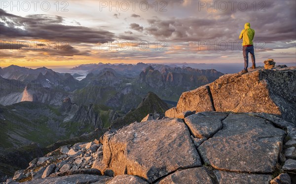 View over mountain top and sea, dramatic sunset, climbers at the top of Hermannsdalstinden,