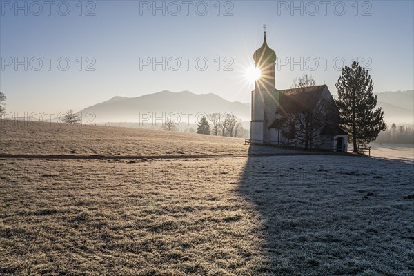 Church backlit with sun in front of mountains, winter, fog, hoarfrost, Sankt Johannisrain,