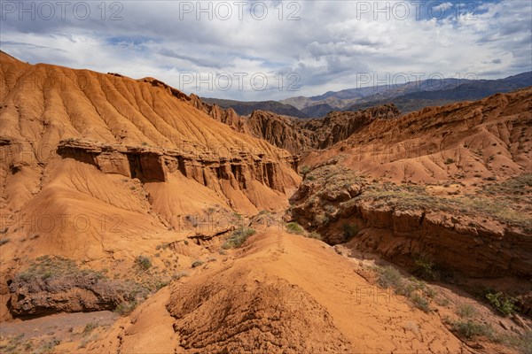 Eroded mountain landscape with sandstone cliffs, canyon with red and orange rock formations,
