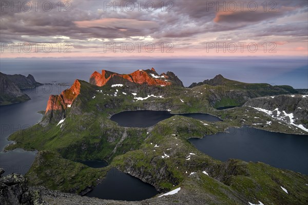 View over mountain peaks and sea, dramatic sunset, from Hermannsdalstinden, with lakes