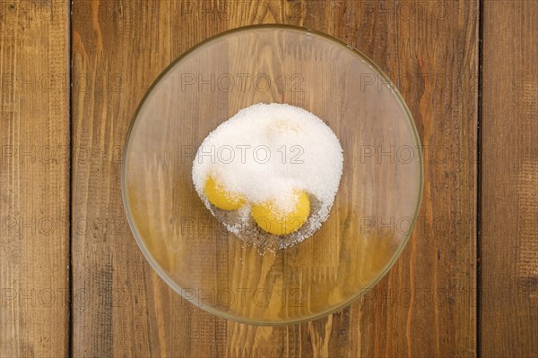 Top view of eggs and sugar in a glass bowl