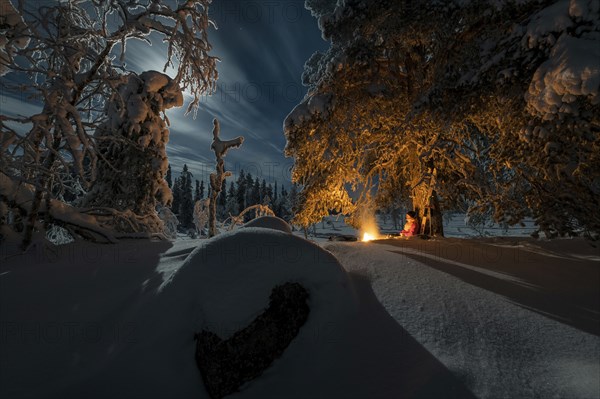 Man in the evening at a bivouac with campfire, Lapland, Sweden, Scandinavia, Europe