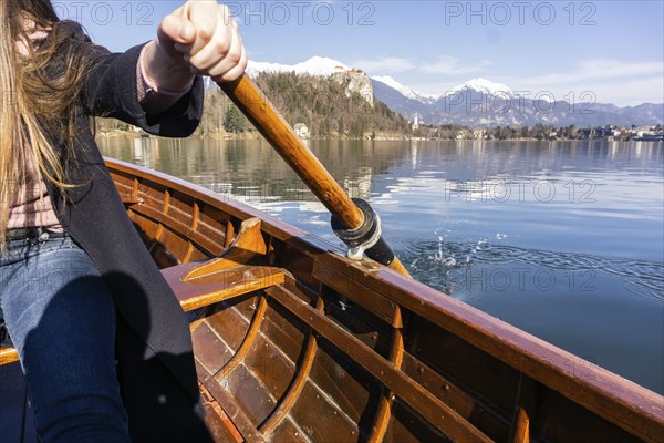 Young woman using paddle on a wooden boat, Lake Bled Slovenia rowing on wooden boats on a sunny day