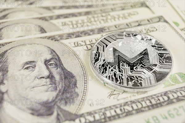 MONERO XMR cryptocurrency, silver monero coin on the background of Dollar bills
