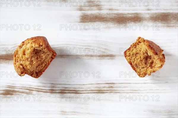 Broken orange muffins on a rustic wooden kitchen table, overhead flat lay shot with copy space,