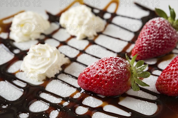 Close up of strawberries and whipped cream with decorations over a white plate