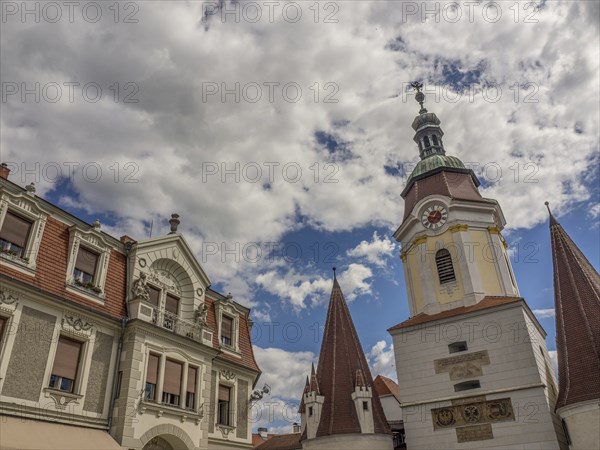 A town with historic buildings and a church tower under a partly cloudy sky, Dürnstein, Wachau,