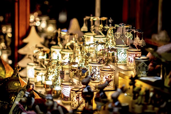 Many decorated Christmas lamps stand as decoration on a table in front of a blurred background