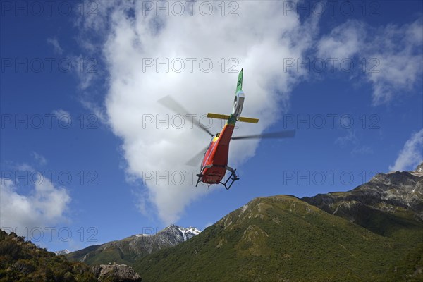 ARTHURS PASS, NEW ZEALAND, 2021-01-29: A brightly painted helicopter takes off from a car park in