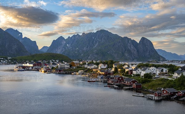 Village view of the fishing village Reine, Traditional red Rorbuer cabins, at sunset, rocky
