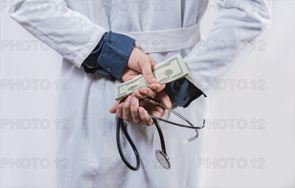 Dishonest doctor hiding money. Medical corruption and bribery concept, Corrupt doctor hiding money