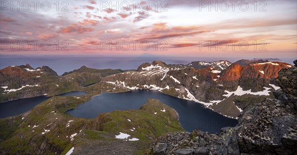 View over mountain top and sea, dramatic sunset, at the summit Hermannsdalstinden, with lakes