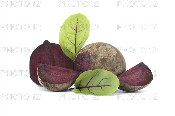 Collection of whole beetroot arranged next to slices of beetroot vegetables with their green leaves