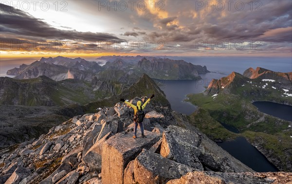 View over mountain top and sea, dramatic sunset, mountaineers at Hermannsdalstinden peak, with