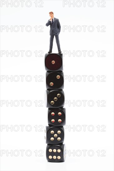 Symbol photo, man (figure) standing perplexed on a stack of dice showing the values 1 to 6 in