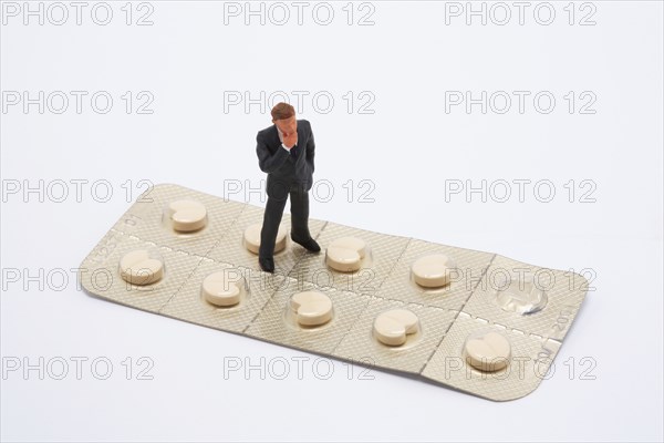 Symbol photo, man (figure) standing helplessly on a blister with tablets, side effect