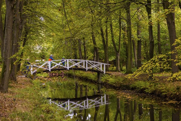 Cyclists pass a bridge in Hermsdorf Castle Park near Dresden